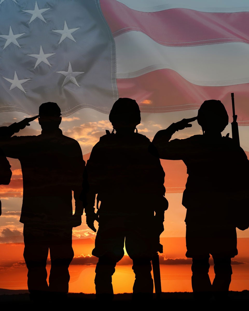 US soldiers saluting with an American flag in the background.